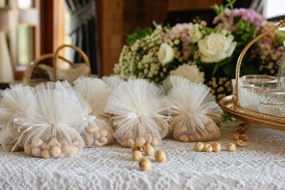 Roasted hazelnut favors wrapped in tulle bundles on a lace-covered table