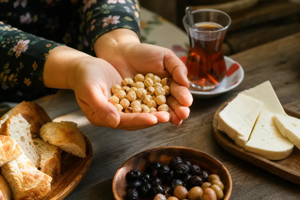 Hands holding a handful of Giresun hazelnuts over a breakfast table